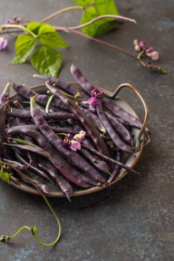 Siyah bir masada taze mor dize fasulye, temiz yemek, seçici odak.