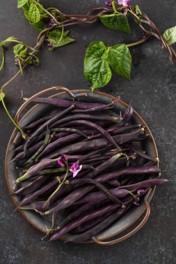 Siyah bir masada taze mor dize fasulye, temiz yemek, seçici odak. Üstte görüntü.