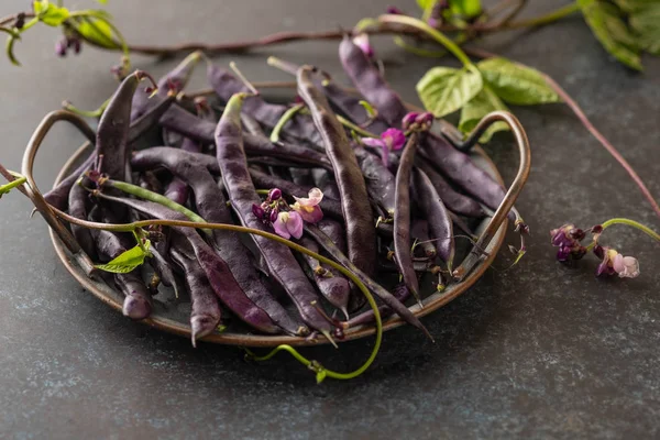 Färska lila sträng bönor på ett svart bord, ren mat, selektiv fokus. — Stockfoto