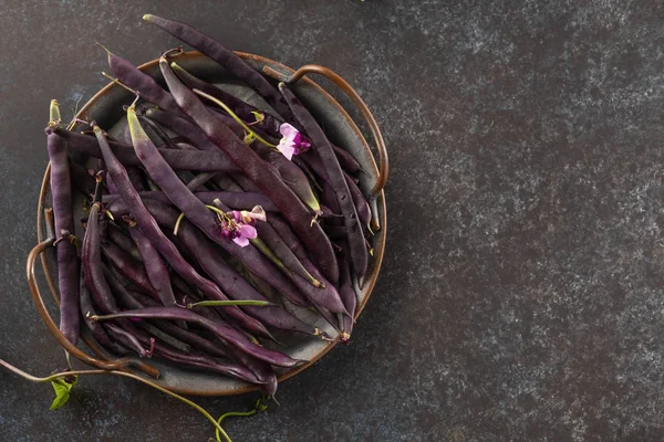 Fresh purple string beans on a black table, clean eating, selective focus. Top view.