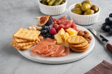 Et ve peynir tabağı. Geleneksel İtalyan antipastosu, salamlı kesme tahtası, soğuk füme et, kraker, gri arka plan üzerine zeytin. Peynir ve et mezesi.