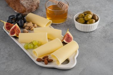 Bal, incir, zeytin, üzüm ile beyaz tahta üzerinde peynir dilimleri.