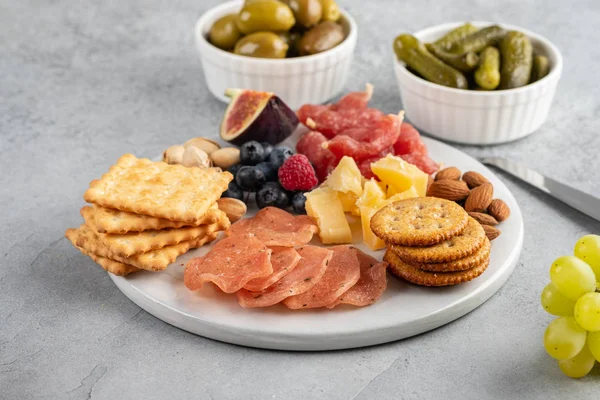 Prato de carne e queijo.Antipasto italiano tradicional, tábua de corte com salame, carne fria defumada, biscoitos, azeitonas em fundo cinza. Aperitivo de queijo e carne . — Fotografia de Stock