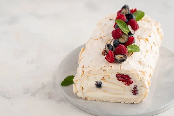Meringue roll cake with cream and raspberries. Roulade, summer dessert, closeup.