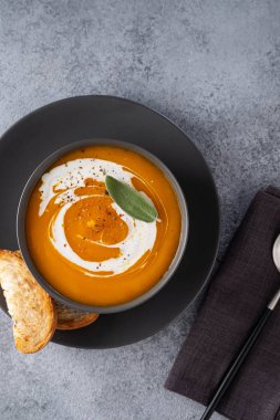 Gri arka planda adaçayı ile kabak çorbası. Üstte görüntü.