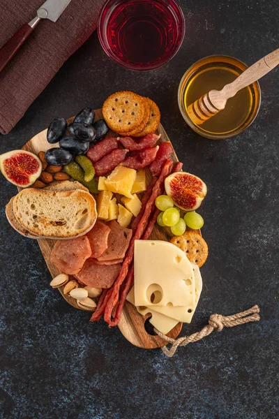 Antipasto prato de catering com bacon, jerky, salsicha, azeitona, queijo e uvas em uma tábua de madeira. Vista superior . — Fotografia de Stock