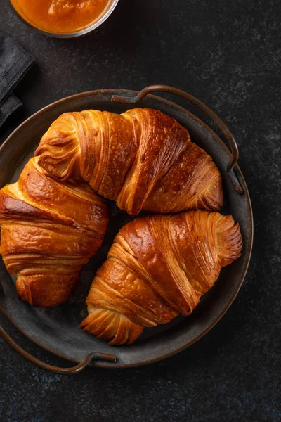 Croissants recém-assados na bandeja vintage. montão de croissants recém-assados no fundo escuro. Pastelaria francesa — Fotografia de Stock