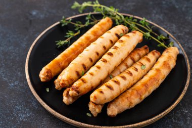 Domates sosu ve kekik ile siyah tabakta ızgara sosis. Boşluğu kopyala.