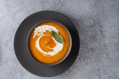 Gri arka planda adaçayı ile kabak çorbası. Üstte görüntü.