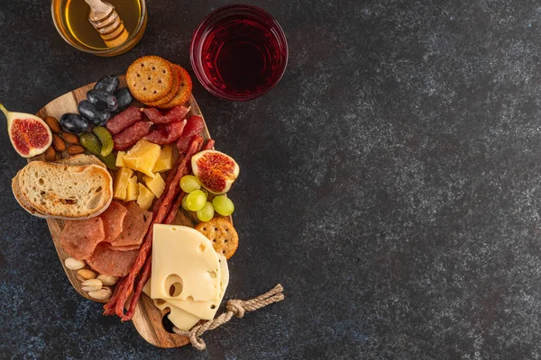 Antipasto prato de catering com bacon, jerky, salsicha, azeitona, queijo e uvas em uma tábua de madeira. Vista superior . — Fotografia de Stock