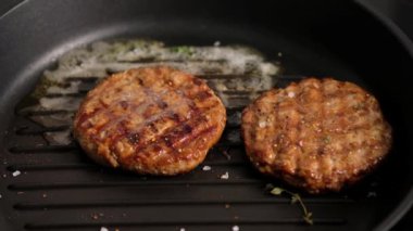 Izgarada ızgara hamburger. Burger pirzolası ızgara tavasında pişirilir, kekik, buhar, duman, ateş. Tereyağı erimiş. Izgara yemek. Yavaş çekim.