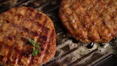 Izgarada ızgara hamburger. Burger pirzolası ızgara tavasında pişirilir, kekik, buhar, duman, ateş. Tereyağı erimiş. Izgara yemek. Yavaş çekim.