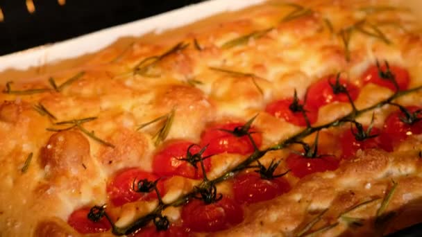 Samice wyjmują focaccia z piekarnika, przygotowują włoski chleb - focaccia z oliwą z oliwek, pomidorami, przyprawami, rozmarynem i solą morską. Ciasto za chleb. Przygotowanie focaccia - Pizza. Zbliżenie. — Wideo stockowe