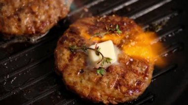 Izgarada ızgara hamburger. Burger pirzolası ızgara tavasında pişirilir, kekik, buhar, duman, ateş. Tereyağı erimiş. Izgara yemek. Yavaş çekim.