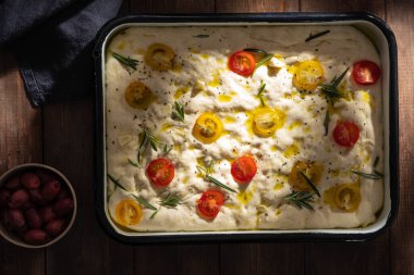 Pişirme kabında çiğ Focaccia hamuru. Geleneksel İtalyan Focaccia biberiyeli, kiraz domatesli ve yağlı. Ev yapımı düz ekmek Focaccia.