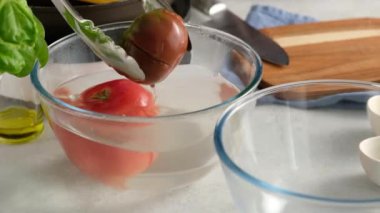 Aşçı soğuk suyla beyaz domates pişirir. Kaynatılmış soğuk su bir domates. Vejetaryen yemekleri pişirmek, mutfakta yemek pişirmek..