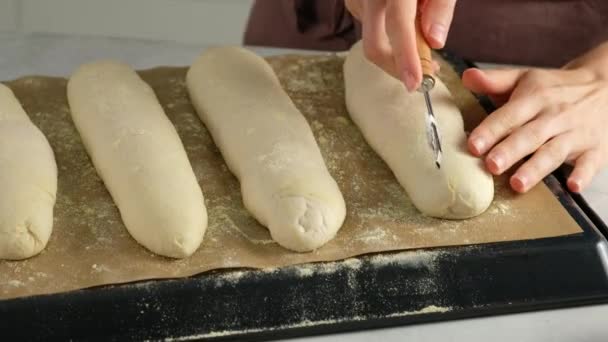 Жіночі руки ріжуть тісто гострим ножем. Французький багет. Хліб. — стокове відео