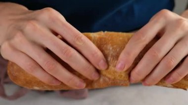Ekmek kırıyorum. Ekmeği ikiye bölen bir kadının elleri. Kadın elleri gevrek Fransız ekmeğini kırıyor..