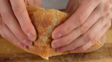 Ekmek kırıyorum. Ekmeği ikiye bölen bir kadının elleri. Kadın elleri gevrek Fransız ekmeğini kırıyor..