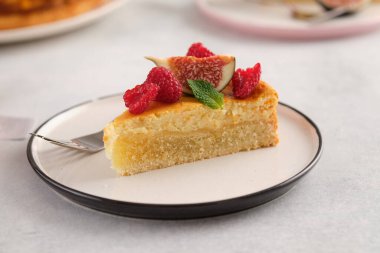 Üzerinde ahududu ve incir olan bir parça peynirli kek..