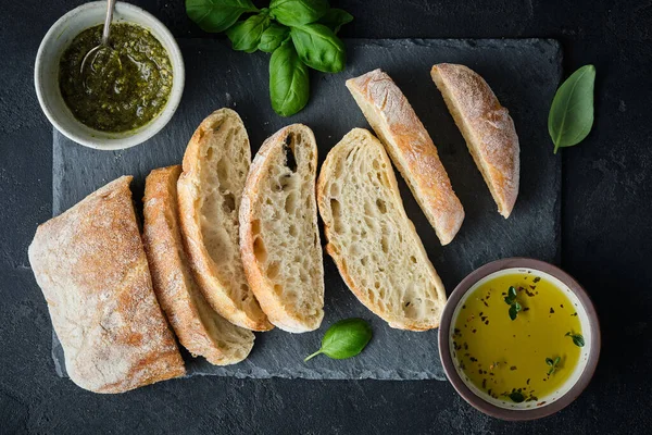 Středomořské svačinky. Olivy, olej, bylinky a krájený ciabatový chléb. Horní pohled. — Stock fotografie