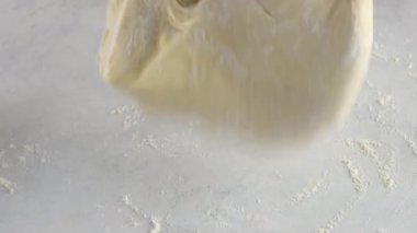 Masada hamuru un ile yoğuran kadın eller, pencereden gelen güneş ışığı sahneyi aydınlatıyor. Kapatın. Tarçınlı çörek üretimi. Fırın ürünleri. Aperatif tarçınlı çörekler