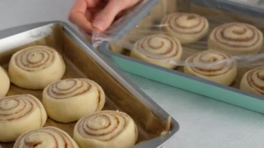 Pasta şefi çiğ tarçın hazırlar. Kadın elleri masada tarçınlı kek hazırlıyor. Kapatın. Tarçınlı çörek üretimi. Fırın ürünleri. Aperatif tarçınlı çörekler