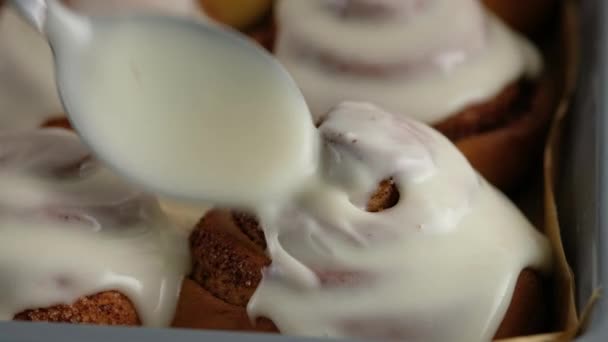 Nalít polevu na čerstvě upečené skořicové rolky nebo Cinnabon zblízka. Sladký smetanový sýr s polevou nalévající se na skořicové závitky. Výroba skořicových rohlíků. Pekařské výrobky. Předkrm skořicové buchty — Stock video