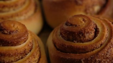 Kadın fırından tarçınlı rulo çıkardı. Tarçınlı ruloların üzerine tatlı krem peynir kreması dökülüyor. Tarçınlı rulo üretiliyor. Fırın ürünleri. Aperatif tarçınlı çörekler