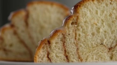 Tarçınlı rulo ekmeği bir tabakta yakın plan kesim. Tarçınlı ruloların üzerine tatlı krem peynirli krema dökülüyor. Tarçınlı çörek üretimi. Fırın ürünleri. Aperatif tarçınlı çörekler