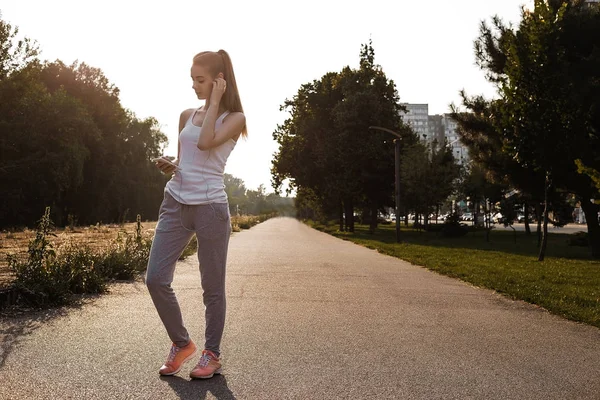 Güzel model, streat kameraya poz. Spor giysileri kızı kulaklık müzik dinle