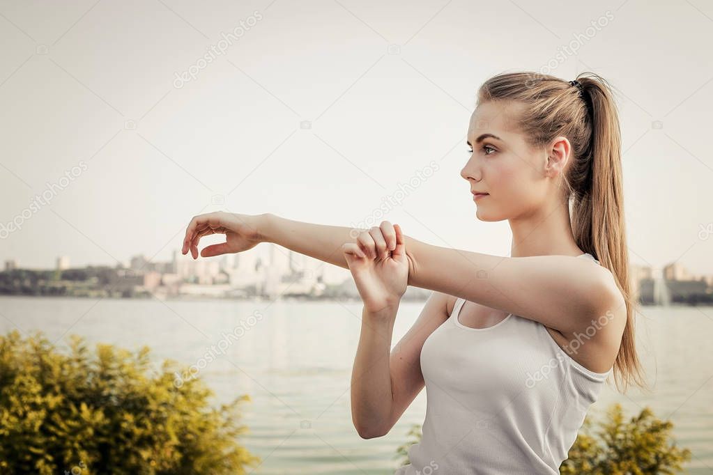 Woman stretching on open air on city and river background.