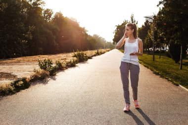 Spor giysileri onun akıllı yol ve dinle müzik üzerinde yürüyen genç ve güzel kızı. Kız onu kulaklık kulağına koydu.. 