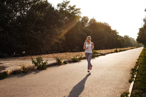Yolda koşu spor genç kız. Sarı saçlı yapmak kardiyo açık olan güzel kadın.