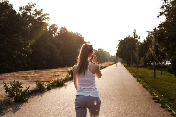 Yolda yürürken spor genç kız. Arka yan görünüm. Açık.