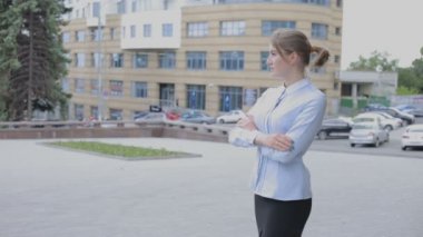 Genç iş kadını ayakta sokakta giyim ve yana doğru seyir kıyafet içinde. Birisi bekliyor ve izlemek arıyorum kız