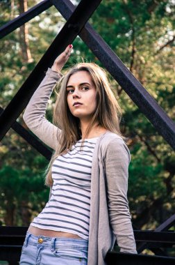 Güzellik genç kadın kameraya poz. Kız siyah şeritler ile beyaz bir kazak ve hırka giyindi. Kameraya bakarak modeli. Açık. Sonbahar. Soğuk. 