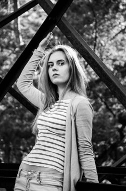 Güzellik genç kadın kameraya poz. Kız siyah şeritler ile beyaz bir kazak ve hırka giyindi. Kameraya bakarak modeli. Açık. Sonbahar. Soğuk. 