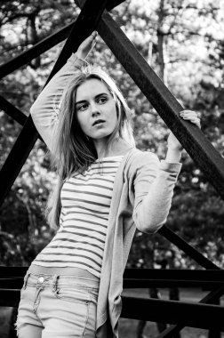 Güzellik genç kadın kameraya poz. Kız siyah şeritler ile beyaz bir kazak ve hırka giyindi. Kameraya bakarak modeli. Açık. Sonbahar. Soğuk. 