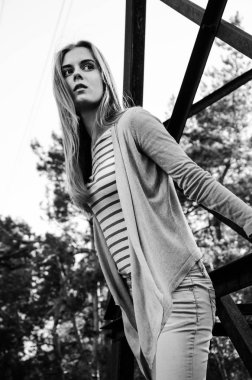 Güzellik genç kadın kameraya poz. Kız siyah şeritler ile beyaz bir kazak ve hırka giyindi. Kameraya bakarak modeli. Açık. Sonbahar. Soğuk. 