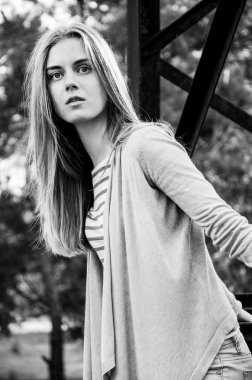 Güzellik genç kadın kameraya poz. Kız siyah şeritler ile beyaz bir kazak ve hırka giyindi. Kameraya bakarak modeli. Açık. Sonbahar. Soğuk. Siyah beyaz portre.