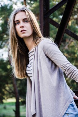 Güzellik genç kadın kameraya poz. Kız siyah şeritler ile beyaz bir kazak ve hırka giyindi. Kameraya bakarak modeli. Açık. Sonbahar. Soğuk. 