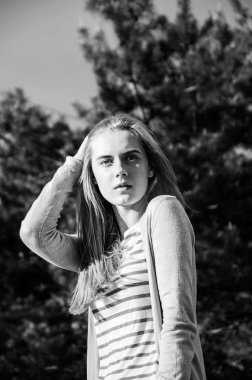 Genç ve güzel kadın mesafe içine bakıyor. Ağaçlar backgorund kameraya poz uzun sarı saçlı kız. Açık. Portre.