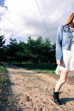 Çerçeve yarısı kadın vücut. Kum yolda yürürken bir kadın. Orman bacground. Açık.