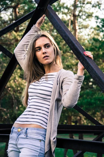 Güzellik genç kadın kameraya poz. Kız siyah şeritler ile beyaz bir kazak ve hırka giyindi. Kameraya bakarak modeli. Açık. Sonbahar. Soğuk. 