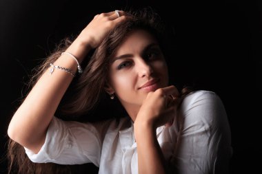 Karamel tenli Genç ve çok güzel bir kadın. Kız kameraya bakıyor ve gülümsüyor. Tuching saçları ve sol omuz modeli. Uzun kıvırcık dalgalı kahverengi saçlı Genç ve güzel kadın portresi