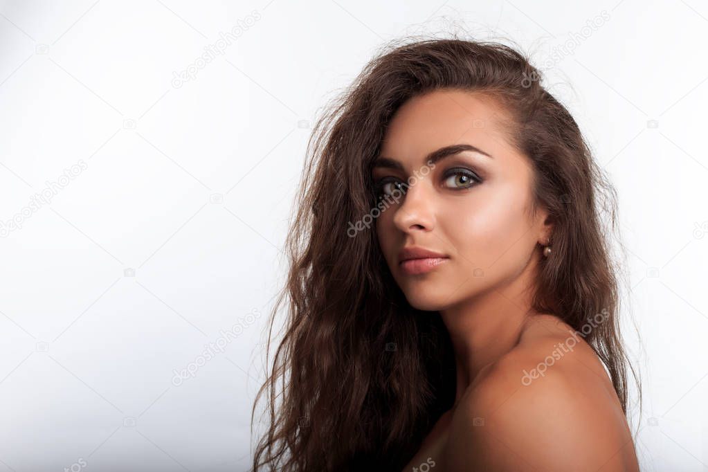 Portrait of pretty young woman with long curly wavy brown hair. Mixed race model with caramel skin looking at camera. 