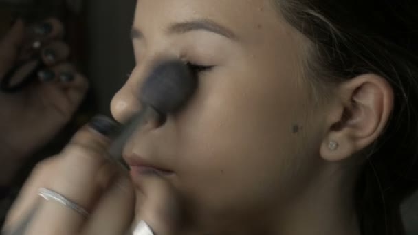 艺术家甚至出模型肤色 化妆师给一个年轻女孩化妆 艺术家在模特脸上变亮肤色 使用画笔 化妆品 面部护理 皮肤护理 — 图库视频影像