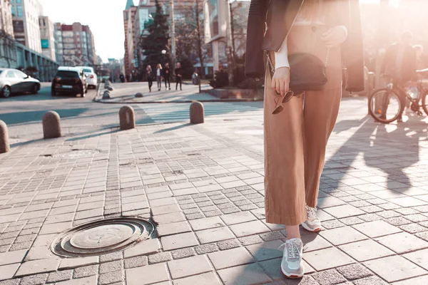 Şık ve şık kız bir deri ceket, spor ayakkabı ve omzunda siyah deri çanta ile şehir etrafında yürüyüş. yatay fotoğraf. Dışında