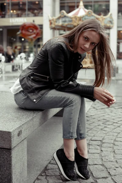 Tam portre, siyah deri ceketli sarışın kadın.